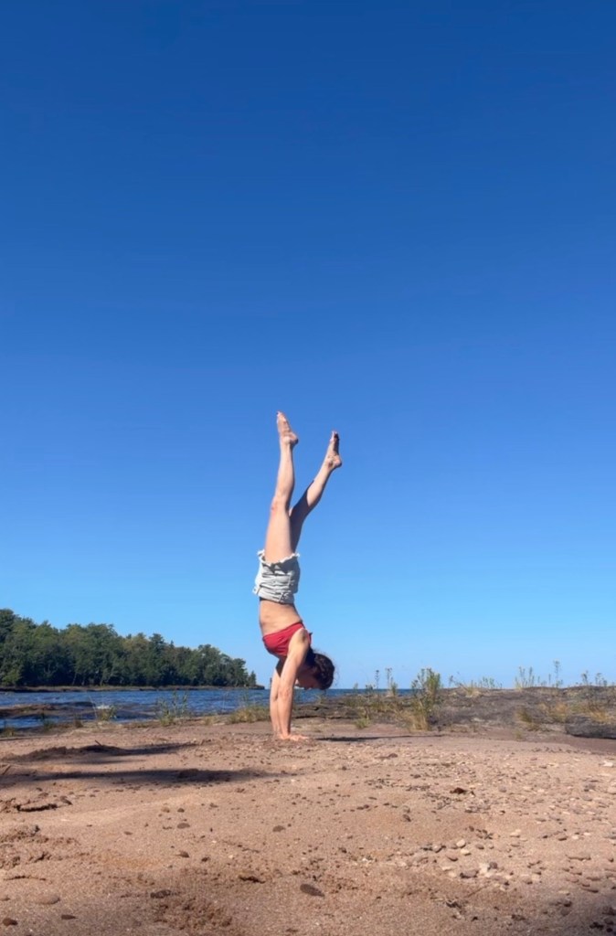 Katrina doing a handstand beside the water.